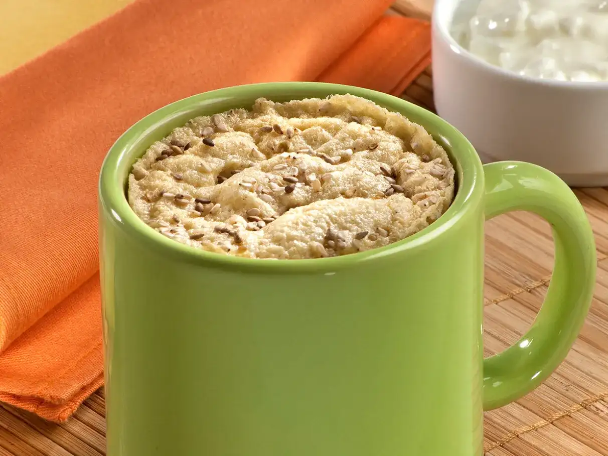 Pão de caneca dourado com sementes na caneca verde